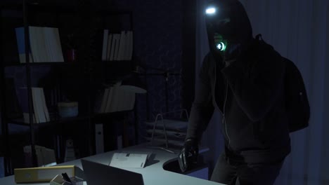 The-thief-man-breaks-into-the-office-and-steals-the-technological-equipment.